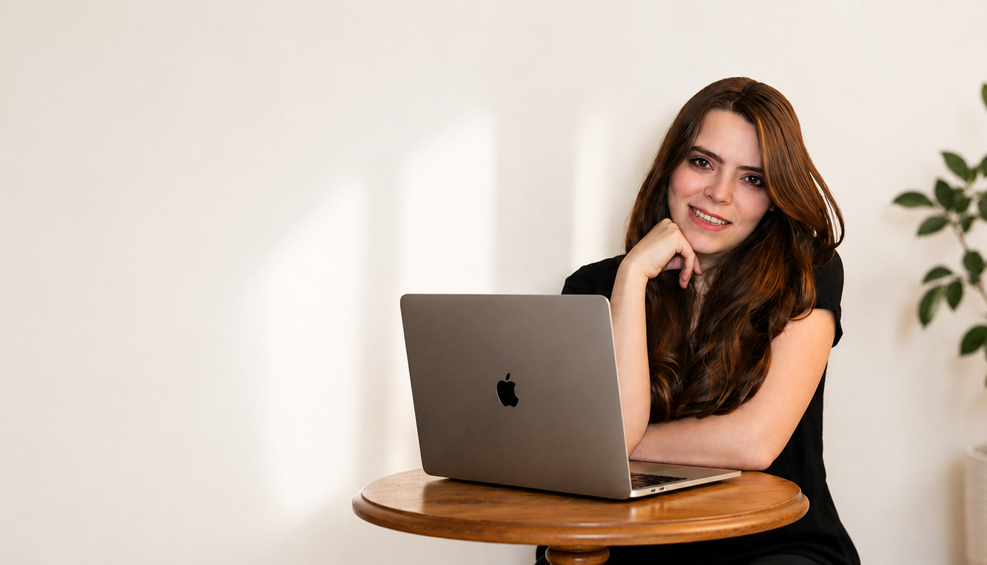 Mariana Capilla smiling while sitting at a wooden table with a laptop